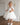 Little girl wearing a luxury white sequin flower girl dress by Aylu Bebe, featuring flutter sleeves and a sparkling tulle skirt, standing in bright modern room. Perfect for weddings, parties and special occasions.