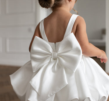 Little girl wearing the Bella Bow white flower girl dress with bubble skirt, back view