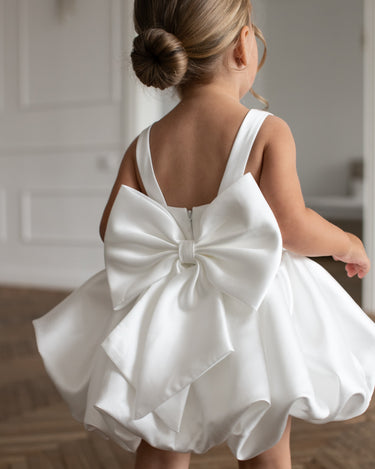 Little girl wearing the Bella Bow white flower girl dress with bubble skirt, back view