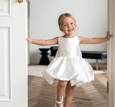 Little girl wearing the Bella bow white flower girl dress with bubble skirt, front view