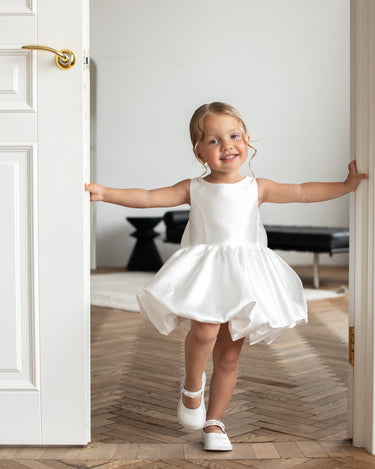 Little girl wearing the Bella bow white flower girl dress with bubble skirt, front view