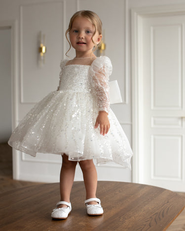 Child posing in Luna sequin dress in natural indoor lighting