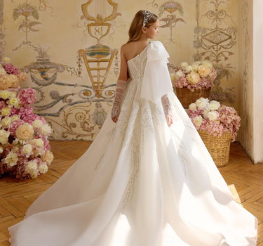 Little girl wearing a luxury one shoulder fairytale gown with dramatic train and sparkling beadwork